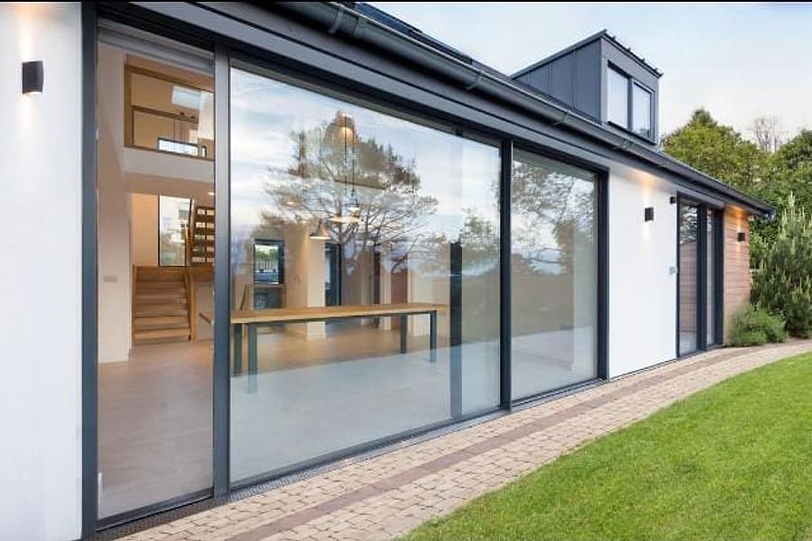 Sliding glass panels in slim dark aluminium frames along the rear of a modern home